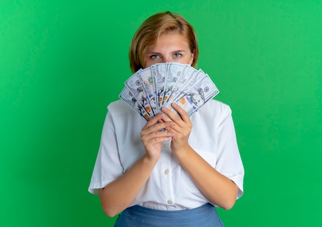 Jeune fille russe blonde confiante regarde l'argent isolé sur fond vert avec copie espace