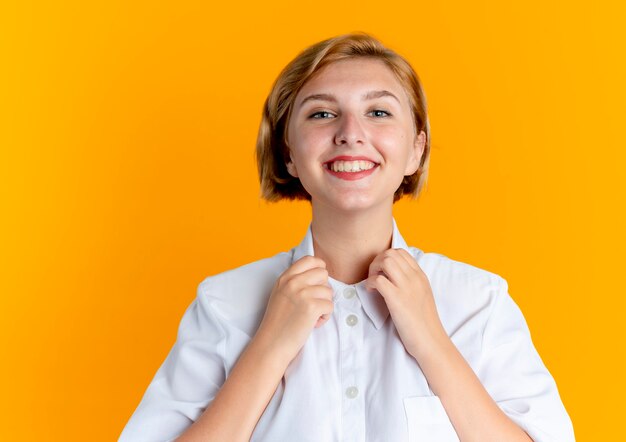 Jeune fille russe blonde souriante tient le collier isolé sur fond orange avec copie espace