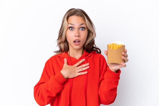 Jeune fille russe tenant des chips frites isolées sur fond blanc surprise et choquée en regardant à droite