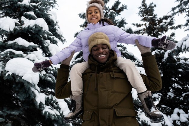 Jeune fille s'amusant avec son père un jour d'hiver enneigé