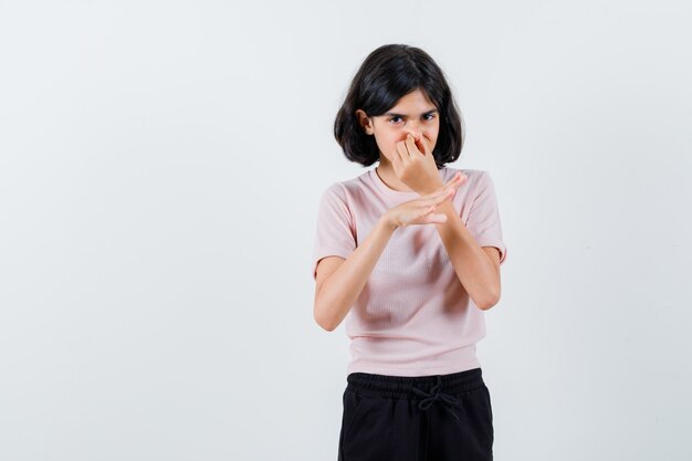 Jeune fille se pincer le nez en raison d'une mauvaise odeur en t-shirt rose et pantalon noir et à la harcelée