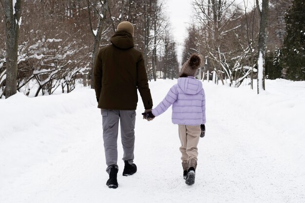 Jeune fille se promenant avec son père en hiver