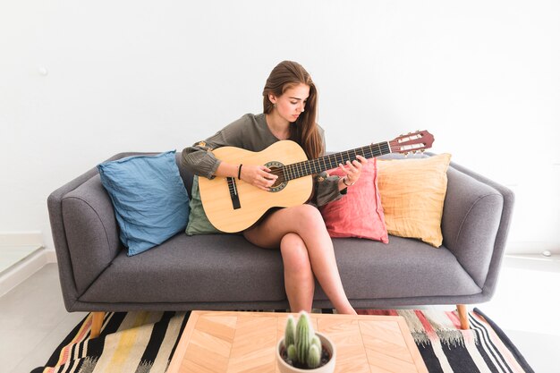 Jeune fille, séance, sofa, jouer guitare