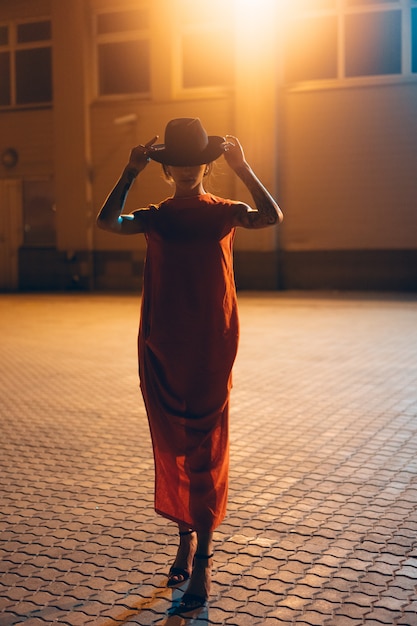 Photo gratuite la jeune fille séduisante dans un chapeau pose à la caméra la nuit