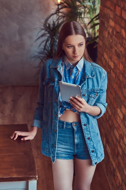 Une jeune fille sexy mince dans une veste en jean et une chemise en flanelle leani