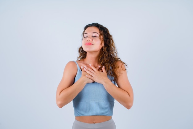 Jeune fille souhaite en mettant les mains sur la poitrine sur fond blanc