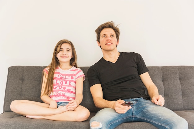 Photo gratuite jeune fille souriante assise sur le canapé avec son père