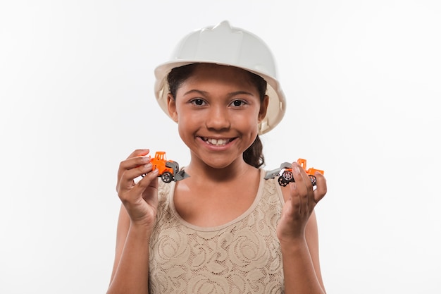 Jeune fille souriante dans le casque tenant des jouets de véhicules commerciaux