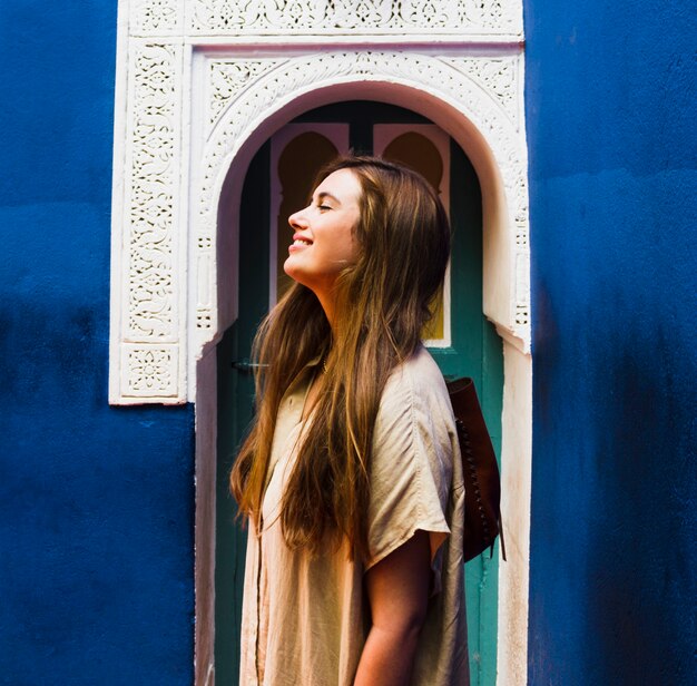 Jeune fille souriante devant la vue de côté de porte cintrée