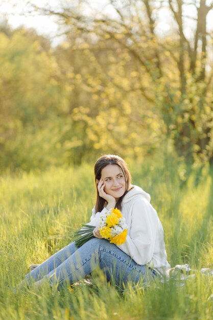 Jeune fille souriante avec des fleurs marchant dans les bois