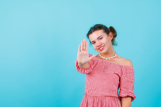 Photo gratuite jeune fille souriante montre sa poignée à la caméra sur fond bleu