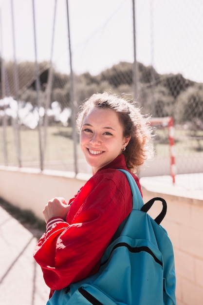 Jeune fille souriante près d&#39;un terrain de sport