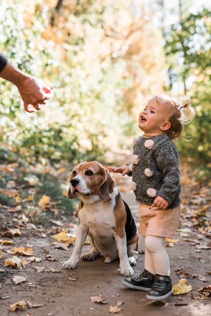 Photo gratuite jeune fille souriante regardant la main de la personne qui nourrit son chien