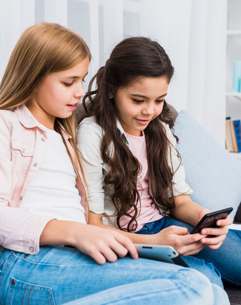 Jeune fille souriante regardant son amie à l&#39;aide d&#39;un téléphone portable