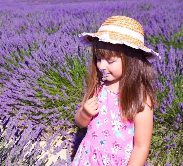 Jeune fille souriante reniflant des fleurs dans un champ de lavande