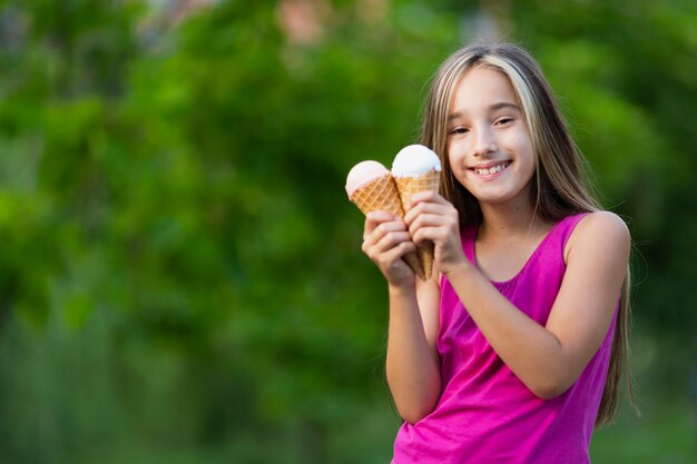 Jeune fille souriante tenant des cornets de crème glacée