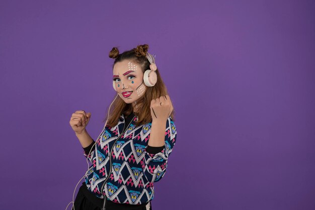 Jeune fille avec stand de maquillage créatif sur fond violet. Photo de haute qualité