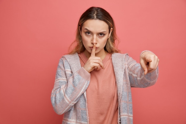 Jeune fille stricte pointant sur le côté faisant un geste de silence