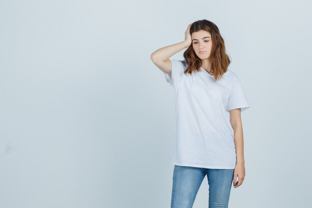 Jeune fille en t-shirt blanc tenant la main sur la tête et à la colère, vue de face.