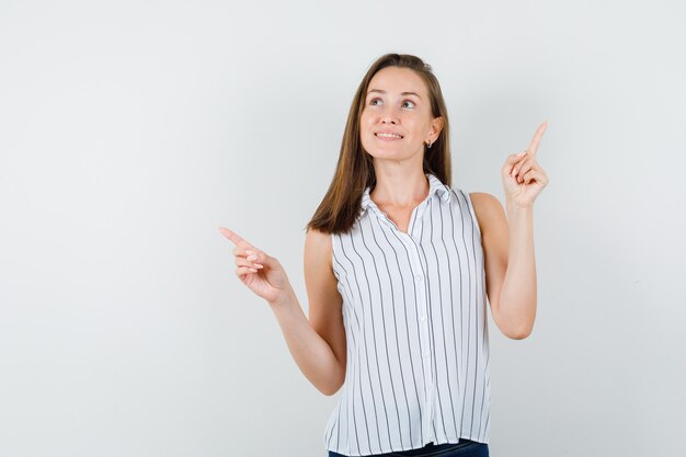 Jeune fille en t-shirt, jeans pointant les doigts vers le haut et à l'espoir, vue de face.