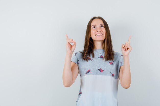 Jeune fille en t-shirt pointant vers le haut et à l'espoir, vue de face.