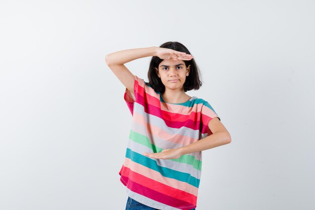 Jeune fille en t-shirt à rayures colorées montrant des écailles et semblant sérieuse, vue de face.