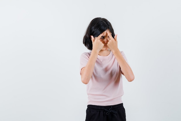 Jeune fille en t-shirt rose et pantalon noir popping un bouton et à la sérieuse