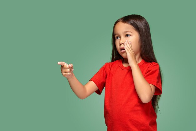 Jeune fille en t-shirt rouge a peur de quelque chose et montre fihger