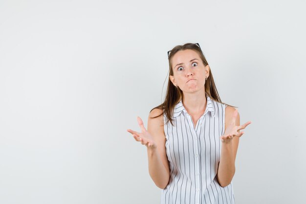 Jeune fille en t-shirt soulevant les paumes de manière agressive et à la vue de face, nerveuse.