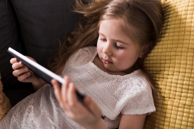 Jeune fille avec une tablette sur le canapé