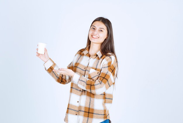 jeune fille avec une tasse de thé se sentant heureuse sur un mur blanc.