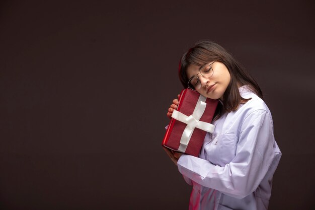 Jeune fille tenant une boîte-cadeau rouge et l'étreignant.