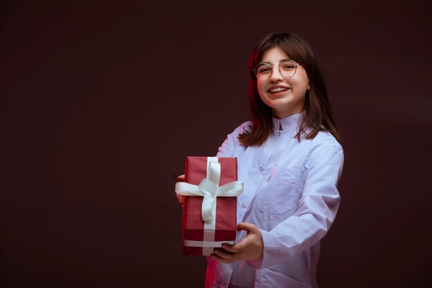 Jeune fille tenant une boîte-cadeau rouge.