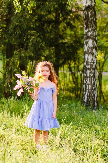 Jeune fille tenant des bouquet de fleurs sauvages dans le parc