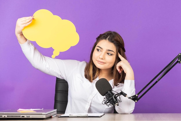 Photo gratuite jeune fille tenant une bulle de papier et pointant le doigt vers sa tête photo de haute qualité