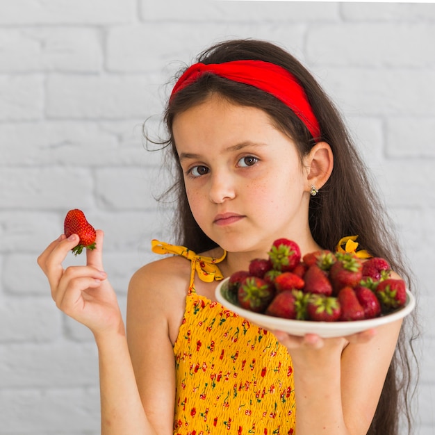 Jeune fille tenant des fraises dans sa main