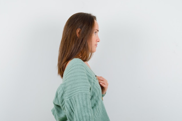 Photo gratuite jeune fille tenant la main sur la poitrine en maille et à la charmante, vue de face.