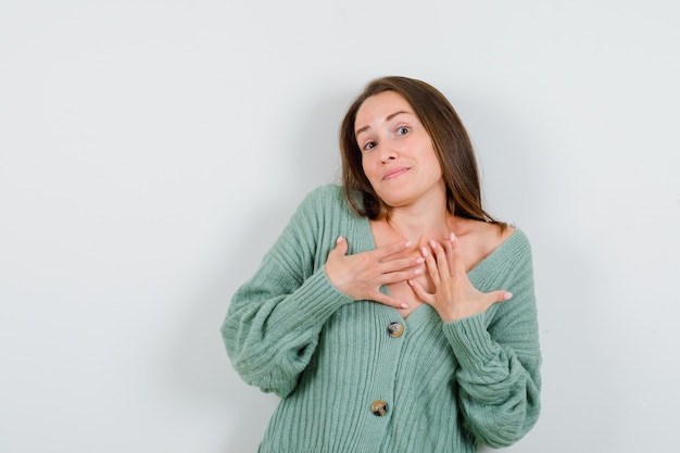 Jeune fille tenant les mains sur la poitrine en maille et à la charmante, vue de face.