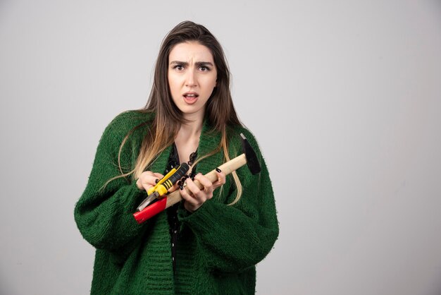 Une jeune fille tenant un marteau et une pince dans ses mains.