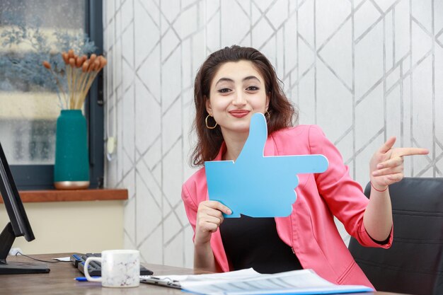 Jeune fille tenant une pancarte et pointez-la de côté Photo de haute qualité