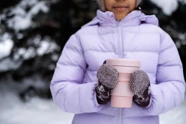 Photo gratuite jeune fille tenant une tasse de boisson chaude à l'extérieur un jour d'hiver