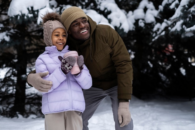 Photo gratuite jeune fille tenant une tasse de boisson chaude lors d'une journée d'hiver avec son père