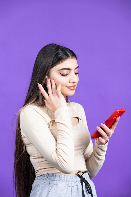 Jeune fille tenant un téléphone et posant sa main sur son oreille Photo de haute qualité