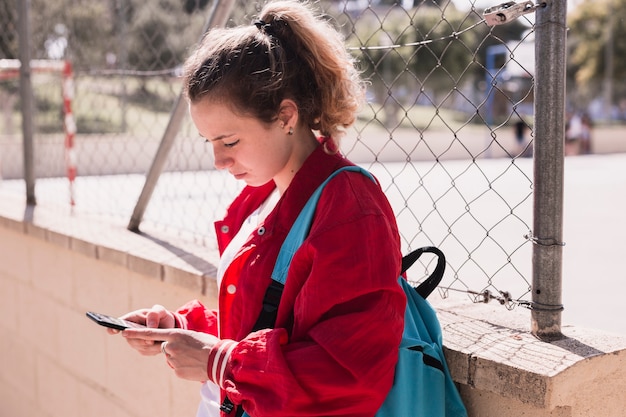 Jeune fille, texte dactylographie, sur, smartphone, près, sportsground