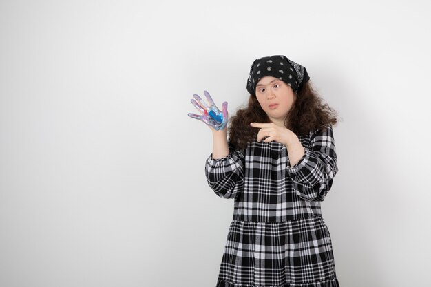 Jeune fille trisomique montrant des couleurs sur blanc.