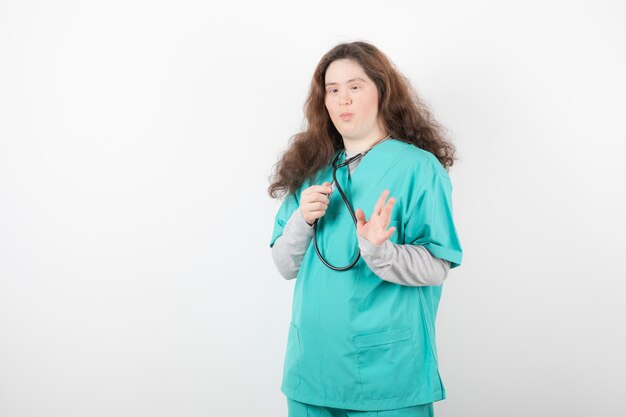 jeune fille trisomique en uniforme vert tenant un stéthoscope.