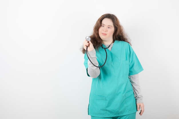 jeune fille en uniforme vert tenant un stéthoscope.