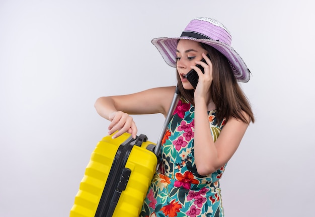 Jeune fille de voyageur caucasien parlant au téléphone avec valise sur fond blanc isolé