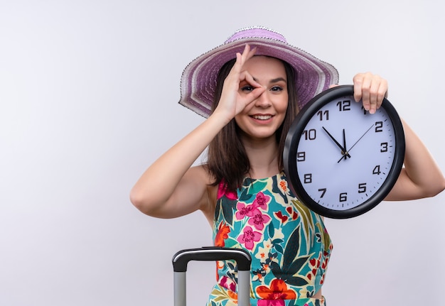 Photo gratuite jeune fille de voyageur caucasien portant chapeau tenant horloge sur fond blanc isolé