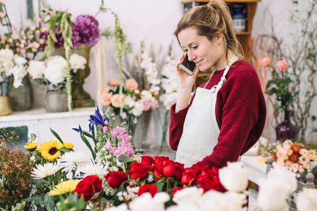 Jeune fleuriste ayant une conversation smartphone